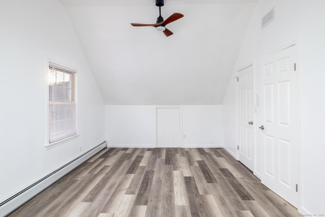 bonus room featuring ceiling fan, baseboard heating, wood-type flooring, and vaulted ceiling