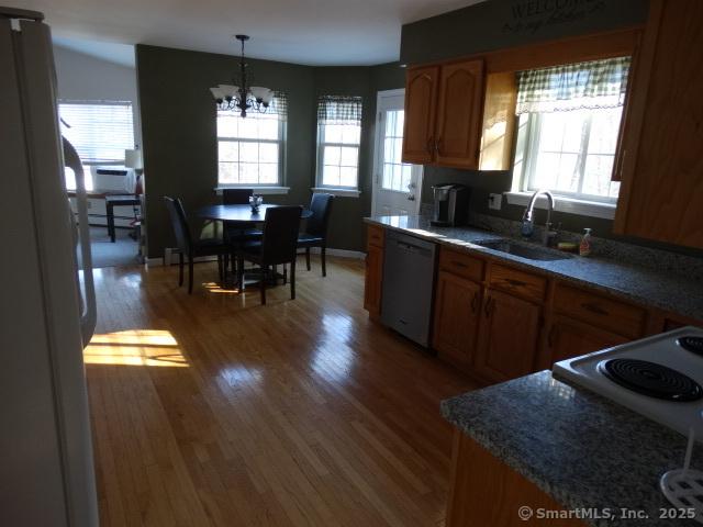 kitchen with refrigerator, stainless steel dishwasher, sink, decorative light fixtures, and a notable chandelier