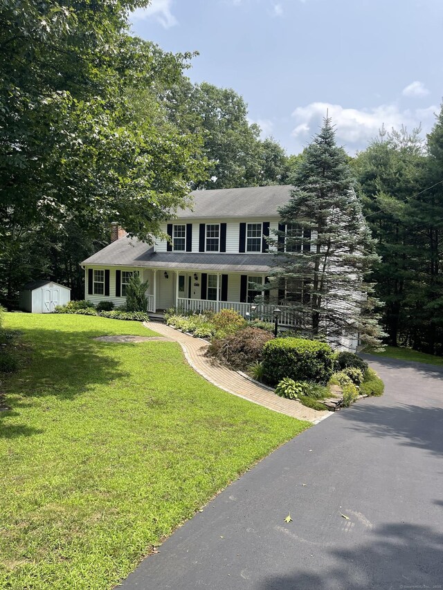 view of front of house with a porch, a shed, and a front lawn