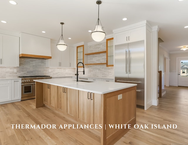 kitchen with white cabinetry, sink, an island with sink, and high end appliances