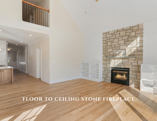 unfurnished living room featuring a high ceiling, crown molding, a fireplace, and light hardwood / wood-style floors