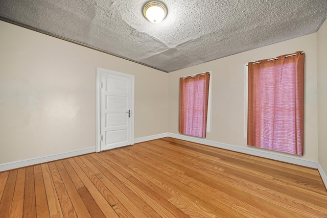 spare room with a textured ceiling and hardwood / wood-style floors