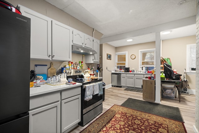 kitchen with a textured ceiling, appliances with stainless steel finishes, light hardwood / wood-style flooring, and white cabinetry