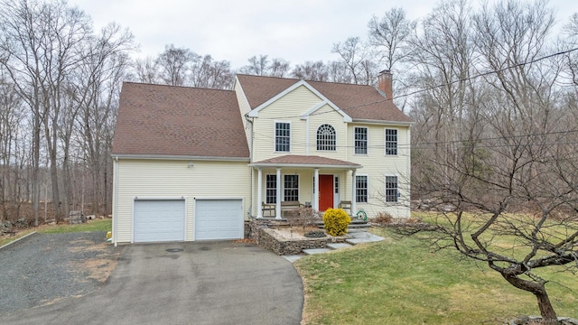 view of front of house featuring covered porch, a garage, and a front lawn