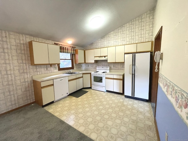 kitchen with cream cabinets, white appliances, lofted ceiling, and sink