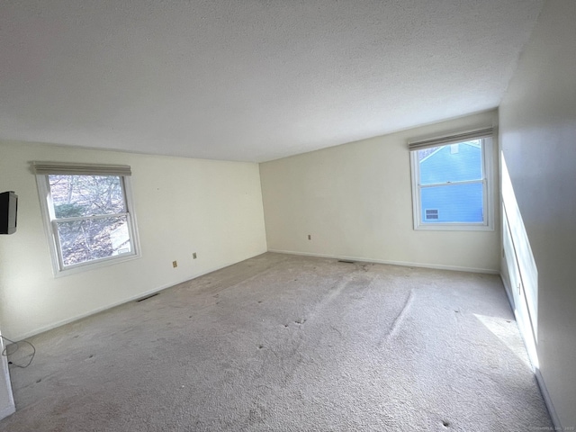 unfurnished room with light carpet and a textured ceiling