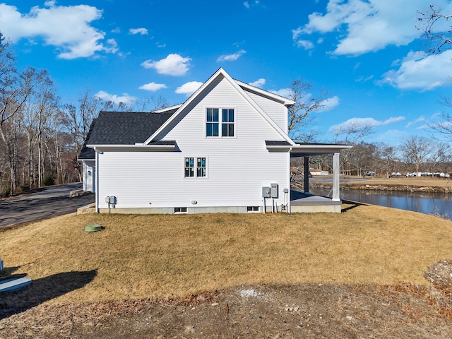 view of side of home with a water view and a lawn