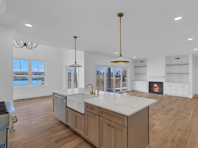 kitchen featuring decorative light fixtures, dishwasher, sink, light stone counters, and a water view