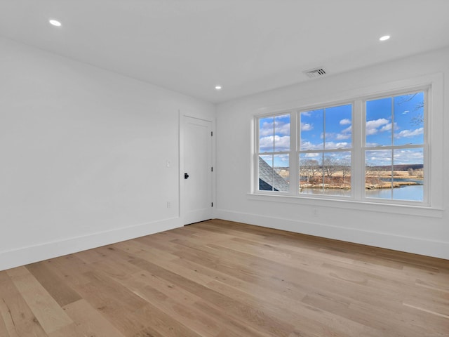 unfurnished room featuring a water view and light hardwood / wood-style floors