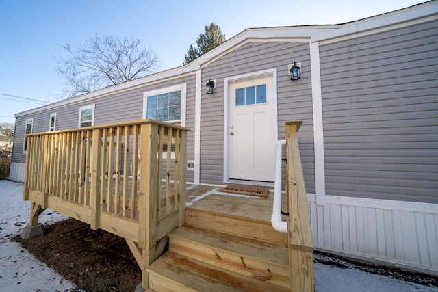 snow covered property entrance with a wooden deck