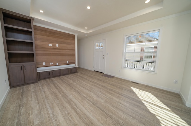 unfurnished living room featuring light wood-type flooring and a tray ceiling