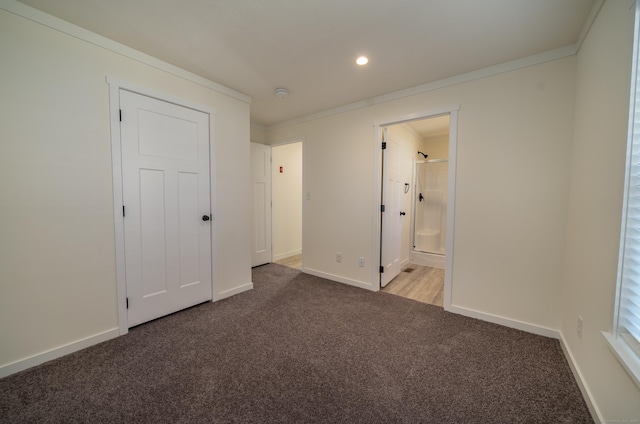 unfurnished bedroom with ensuite bath, crown molding, and carpet floors