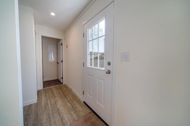 doorway with light hardwood / wood-style floors and ornamental molding