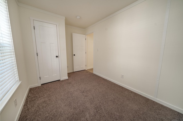 unfurnished bedroom with dark colored carpet and crown molding