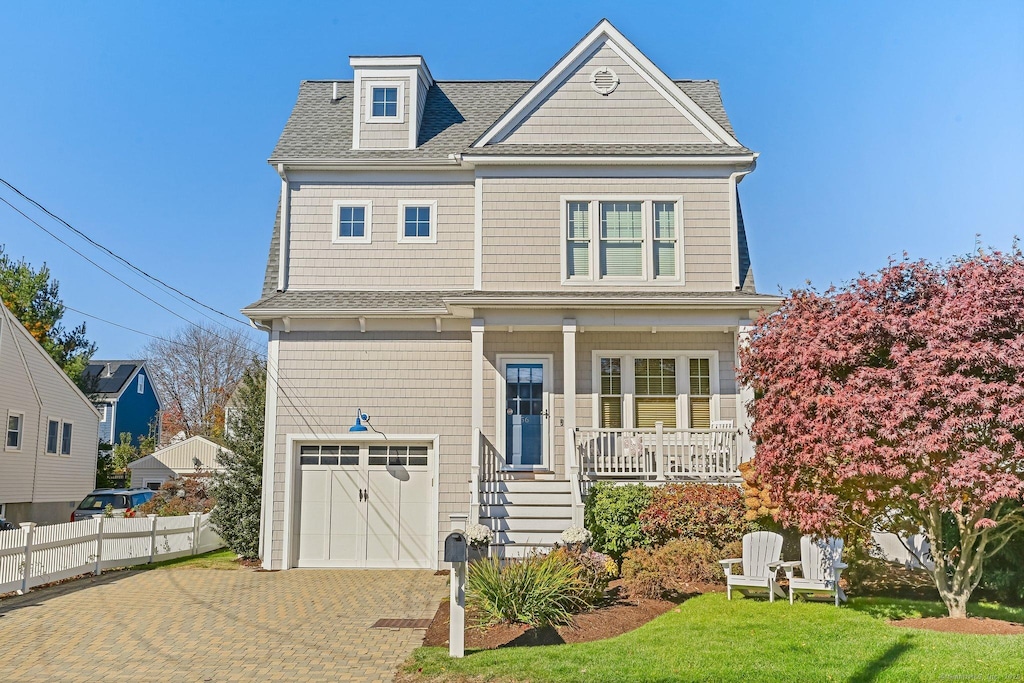 view of front of property with covered porch, a garage, and a front lawn