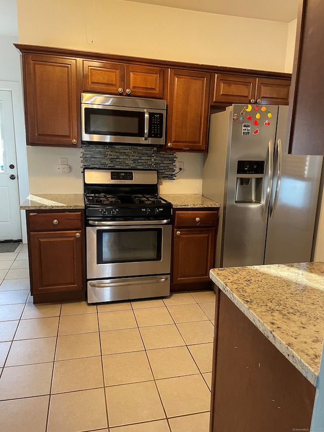 kitchen with light tile patterned floors, appliances with stainless steel finishes, and light stone counters