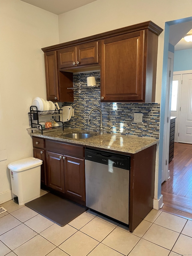 kitchen featuring light tile patterned floors, dishwasher, light stone counters, and sink