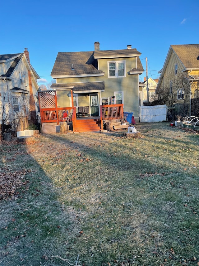 back of property featuring a wooden deck and a yard