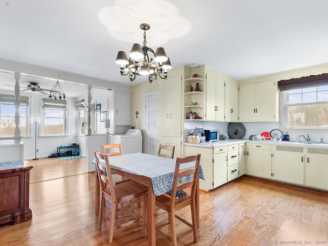 kitchen featuring an inviting chandelier, decorative light fixtures, light wood-type flooring, washer / clothes dryer, and sink