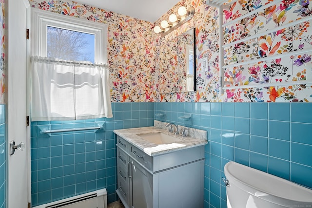 bathroom with a baseboard radiator, a healthy amount of sunlight, wainscoting, and wallpapered walls