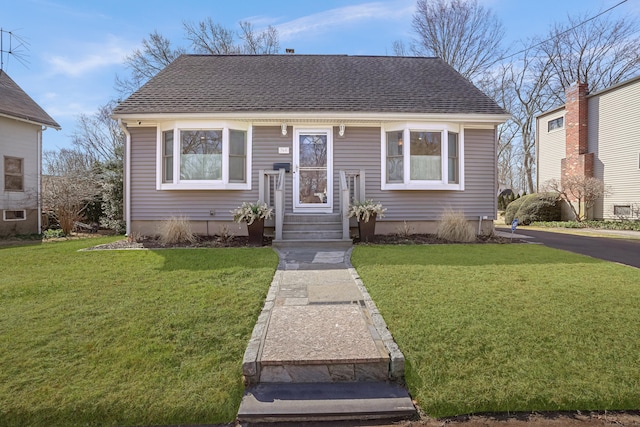 bungalow-style house featuring a front yard and a shingled roof