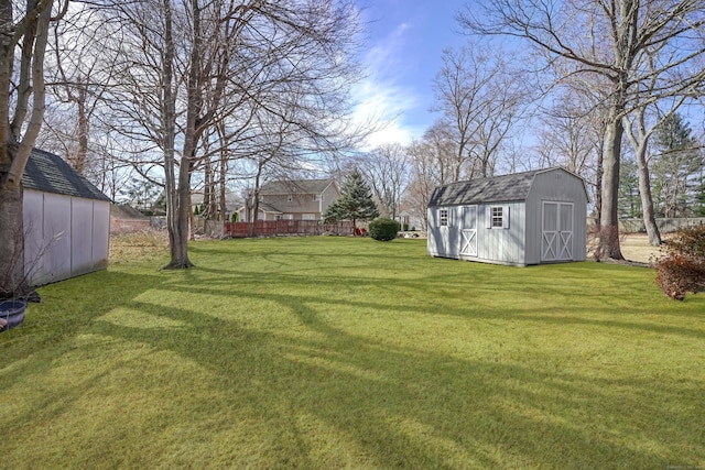 view of yard with a storage shed, an outbuilding, and fence