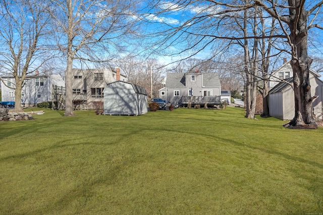 view of yard featuring a shed, a wooden deck, and an outdoor structure