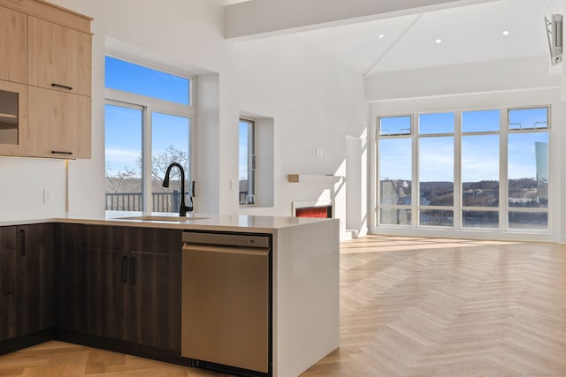 kitchen with stainless steel dishwasher, sink, light brown cabinets, light parquet flooring, and plenty of natural light