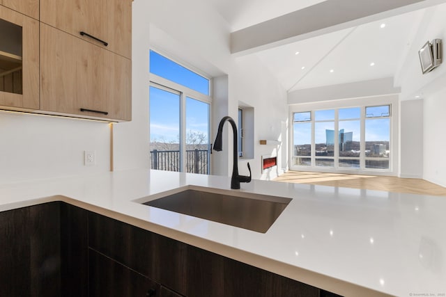 kitchen featuring light brown cabinetry, lofted ceiling with beams, and sink