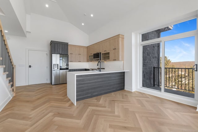 kitchen with kitchen peninsula, appliances with stainless steel finishes, light parquet floors, sink, and high vaulted ceiling