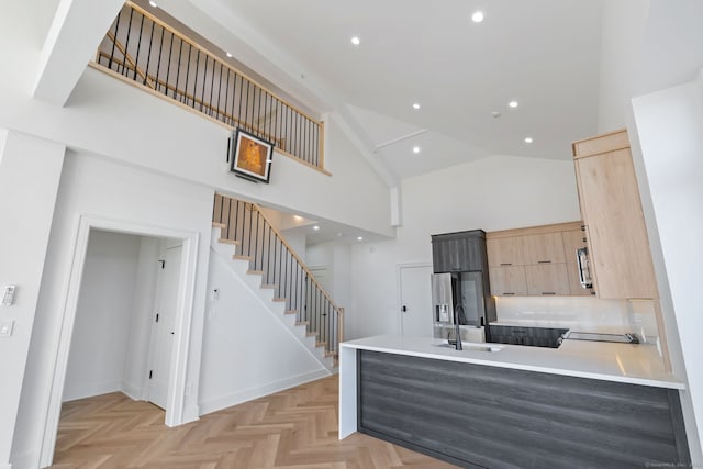 kitchen with sink, high vaulted ceiling, stainless steel refrigerator with ice dispenser, light parquet floors, and light brown cabinetry