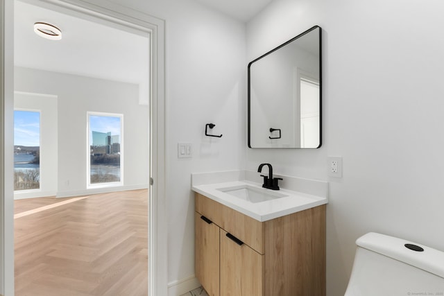 bathroom featuring vanity, parquet flooring, a water view, and toilet