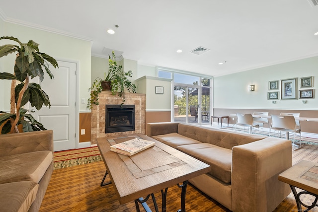 living room with a tile fireplace, crown molding, and hardwood / wood-style floors