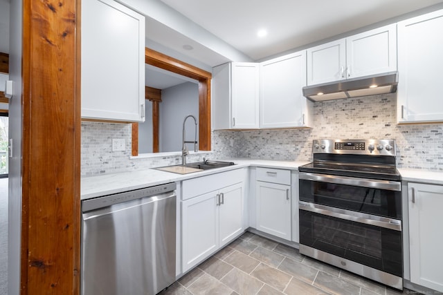 kitchen featuring backsplash, stainless steel appliances, sink, light tile patterned floors, and white cabinetry