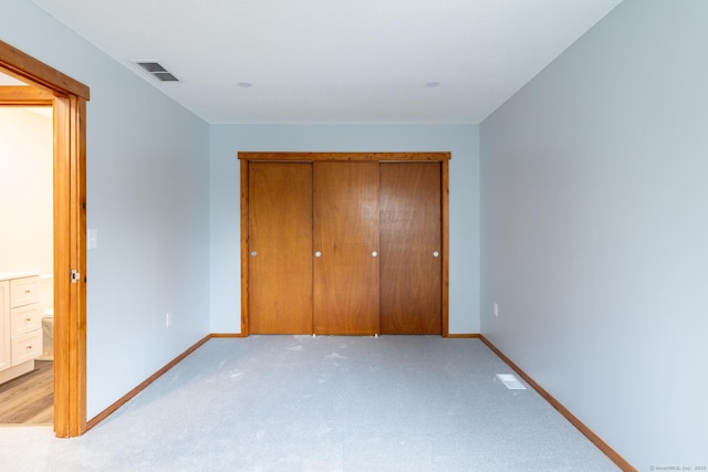 unfurnished bedroom featuring light carpet and a closet