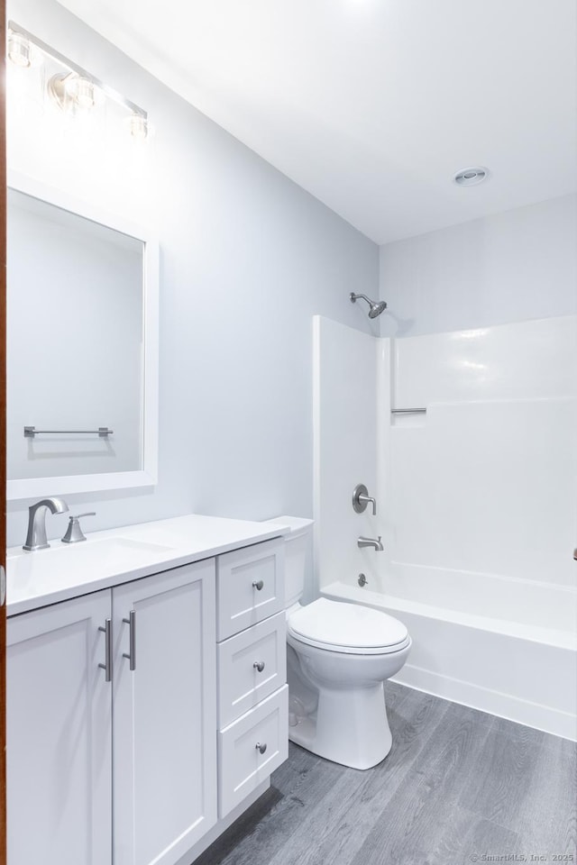 full bathroom featuring hardwood / wood-style floors, vanity, toilet, and tub / shower combination