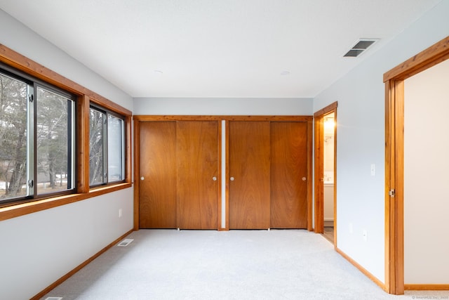 unfurnished bedroom with light colored carpet and a closet