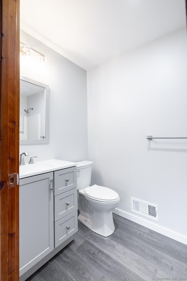 bathroom featuring toilet, vanity, and hardwood / wood-style flooring