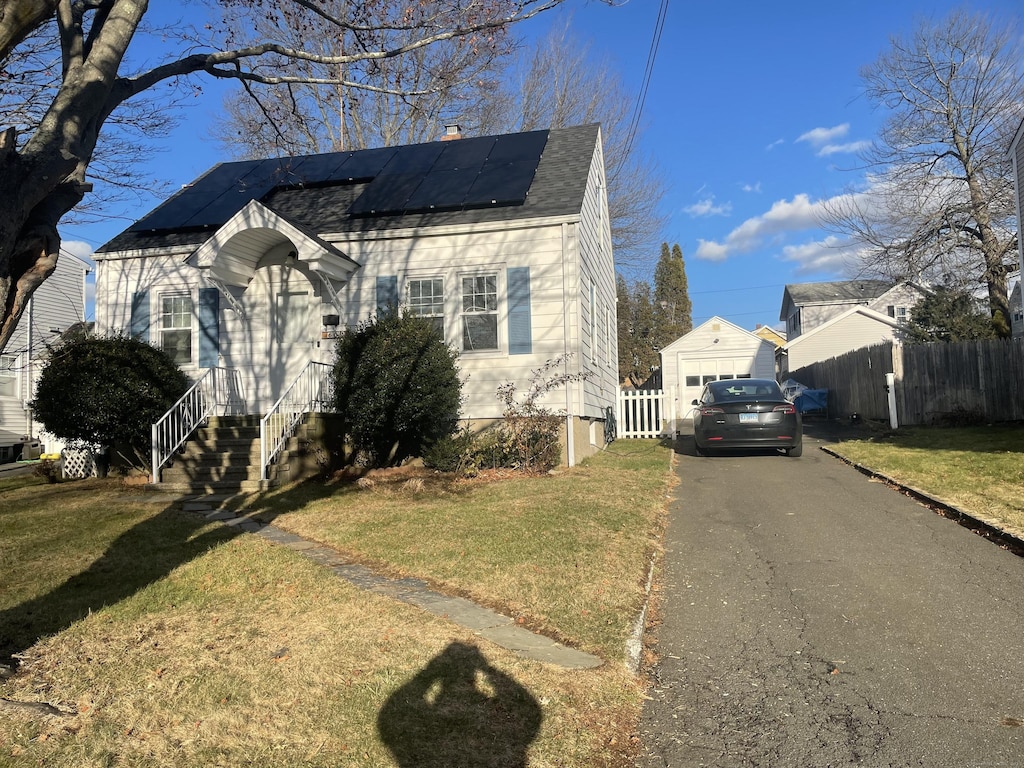 view of front of house featuring solar panels, a garage, an outbuilding, and a front yard