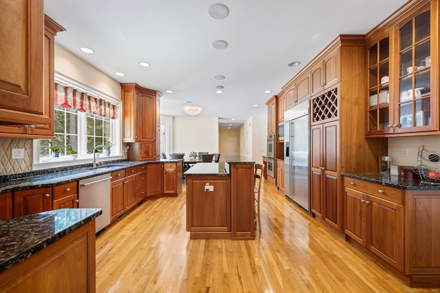 kitchen with a center island, stainless steel appliances, light hardwood / wood-style flooring, and dark stone counters