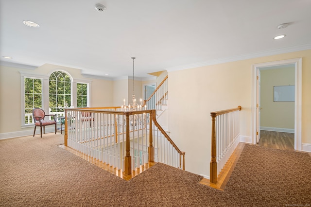 hall with ornamental molding, carpet floors, and an inviting chandelier