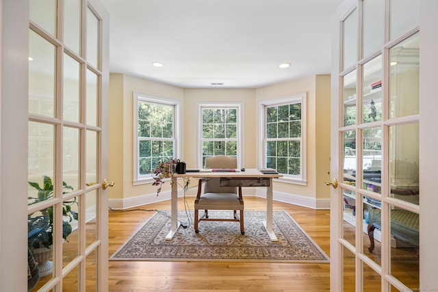 office area with a wealth of natural light, french doors, and light hardwood / wood-style floors