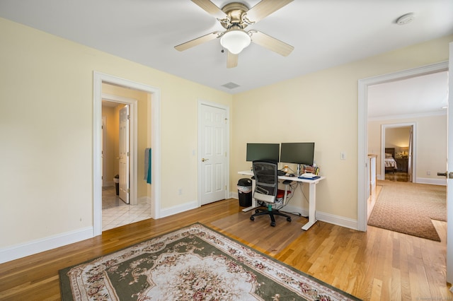 home office with ceiling fan and light hardwood / wood-style flooring