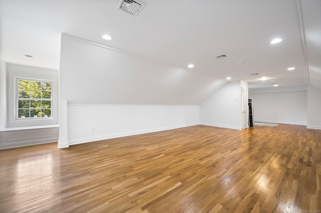 additional living space with wood-type flooring and vaulted ceiling