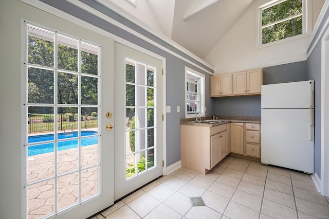 doorway to outside with lofted ceiling, light tile patterned floors, and sink