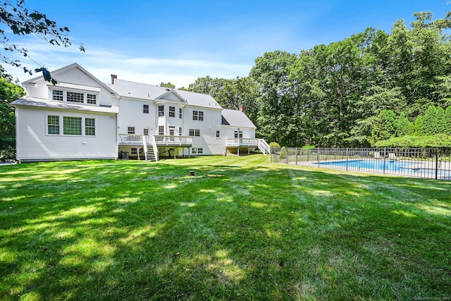 rear view of property with a yard and a pool side deck