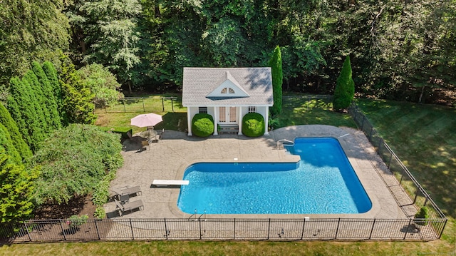 view of pool featuring a diving board, a patio area, an outdoor structure, and a yard