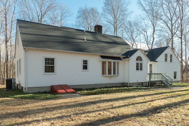 back of property featuring a lawn and central air condition unit