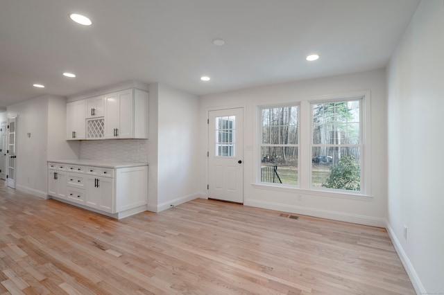 kitchen featuring white cabinetry, light hardwood / wood-style floors, and tasteful backsplash