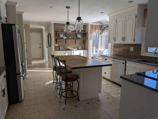 kitchen featuring wooden counters, a sink, stainless steel appliances, a kitchen bar, and backsplash